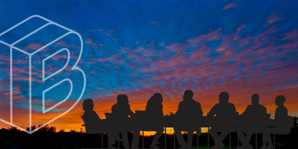 Banner image: People sitting at a board room table with a sunset in the background