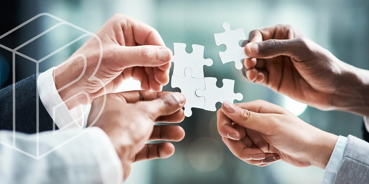 Photo of four hands holding puzzle pieces, assembling them together