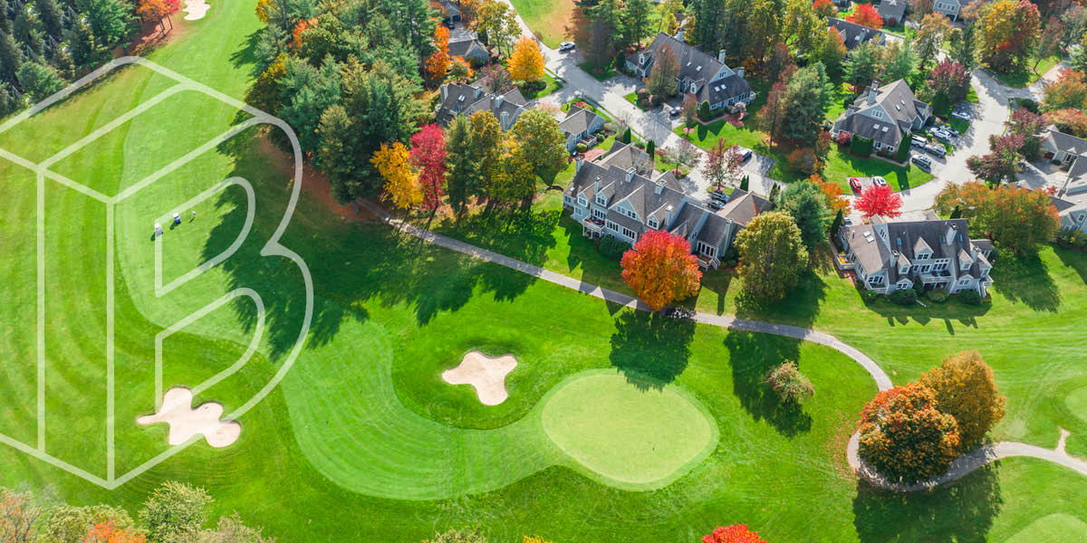 Banner Image of a bright green golf course beside stone buildings